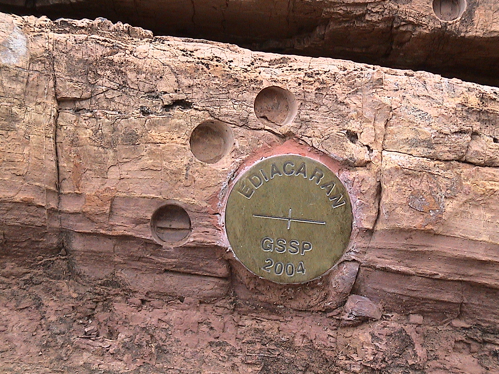 หมุดทองระบุตำแหน่งชุดหินอ้างอิง (GSSP) ของยุคเอเดียคาเรน (Ediacaran Period) ในประเทศออสเตรเลีย รอยวงกลมบนหินคือตำแหน่งที่เก็บตัวอย่างหินสำหรับการศึกษาการเปลี่ยนแปลงสนามแม่เหล็กโลก